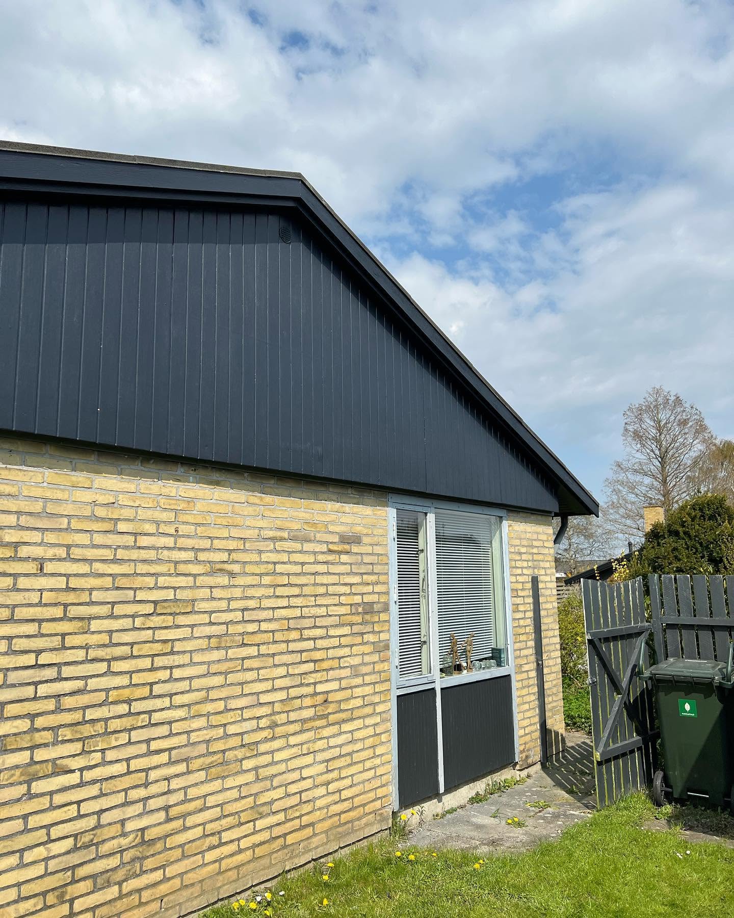 Færdigmalet mørk trægavl over gul murstensfacade