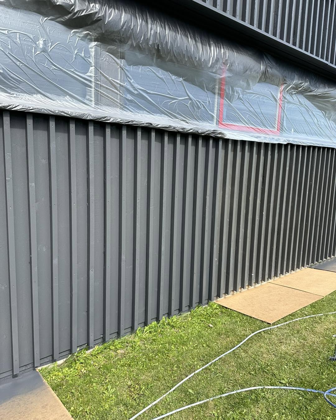 Facade under malerarbejde med omhyggeligt afdækkede vinduer
